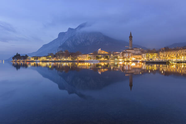 Dusk on Lecco city reflected in the lake Como, Coltignone mount wrapped by clouds, Lombardy, Italy, Europe