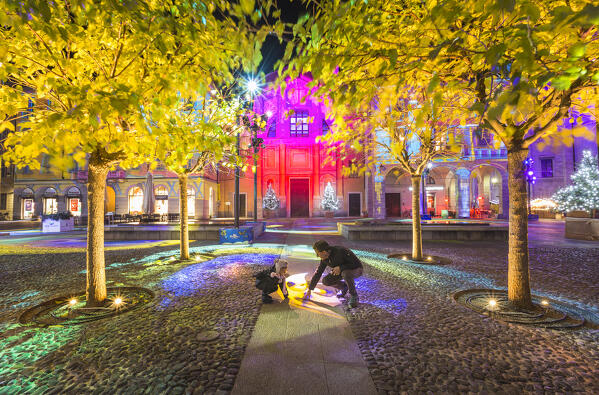 Child and grandfather plays with the lights of Città dei Balocchi in the Christmas time, Piazza Guido Grimoldi square, Como city, Lombardy, Italy, Europe (MR)