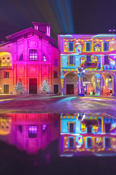 Piazza Guido Grimoldi reflected in a fountain illuminated at night during the Christmas time, Città dei Balocchi, Como city, Lombardy, Italy, Europe