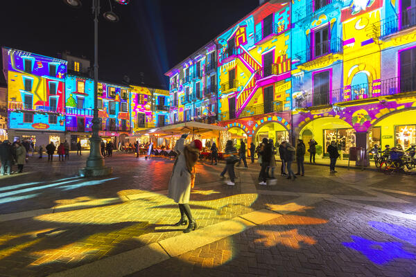 Woman take a picture of Broletto and Santa Maria Assunta cathedral illuminated by night in the Christmas time, Piazza del Duomo square, Città dei Balocchi, Como city, Lombardy, Italy, Europe