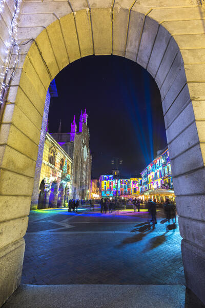 The arch of Portici Plinio frame Broletto and Santa Maria Assunta cathedral illuminated by night in the Christmas time, Città dei Balocchi, Como city, Lombardy, Italy, Europe