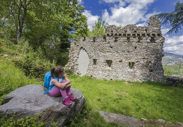 A little girl relaxing and looking the ruin near the Castel Baradello after walking in the Spina Verde, Como, lake Como, Lombardy, Italy, Europe (MR)