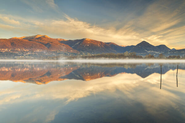 Morning light illuminates the Bollettone mount and Como mountains reflected on Alserio lake, Parco regionale della Valle del Lambro, Brianza, Como province, Lombardy, Italy, Europe