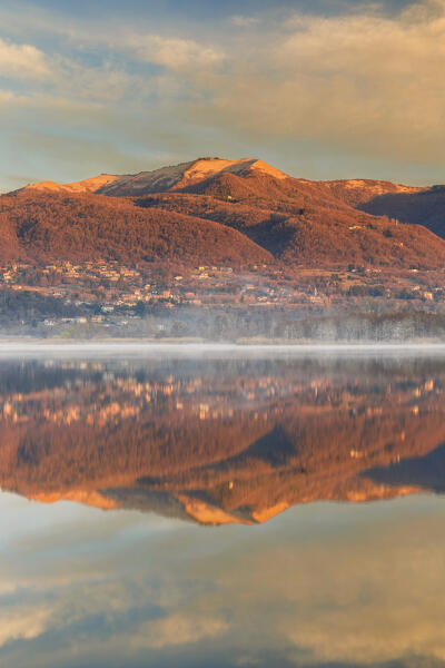Morning light illuminates the Bollettone mount reflected on Alserio lake, Parco regionale della Valle del Lambro, Brianza, Como province, Lombardy, Italy, Europe