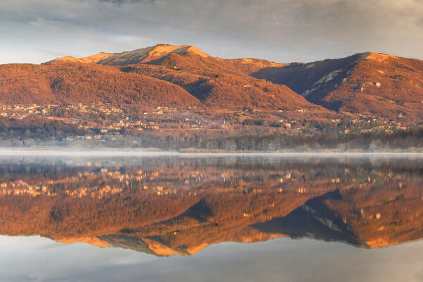 Morning light illuminates the Bollettone mount reflected on Alserio lake, Parco regionale della Valle del Lambro, Brianza, Como province, Lombardy, Italy, Europe