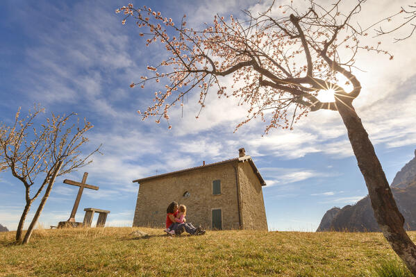 Mom and daughter hug each other surrounded by the Almond (Prunus dulcis) trees, Piana di San Tomaso, Valmadrera, lake Como, Lecco province, Lombardy, Italy, Europe (MR)