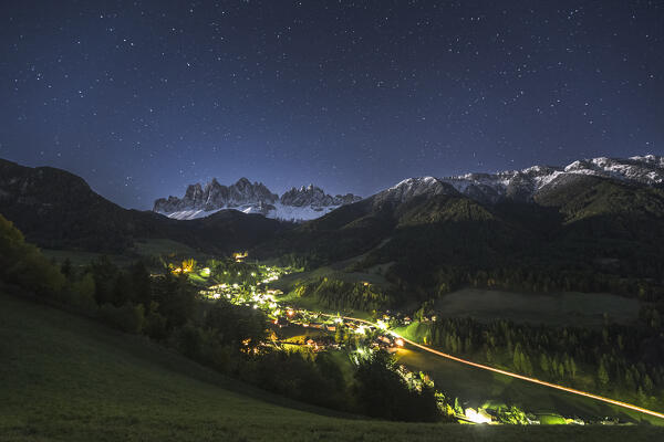 A starry sky over Funes valley with the village of Santa Magdalena illuminated at night, Odle Dolomites, South Tyrol, Trentino Alto Adige, Bolzano province, Italy, Europe