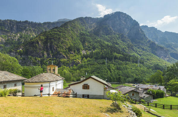 A trekker take rest looking the Vho village, Via Spluga path, San Giacomo Filippo, Chiavenna valley, Sondrio province, Lombardy, Italy, Europe (MR)