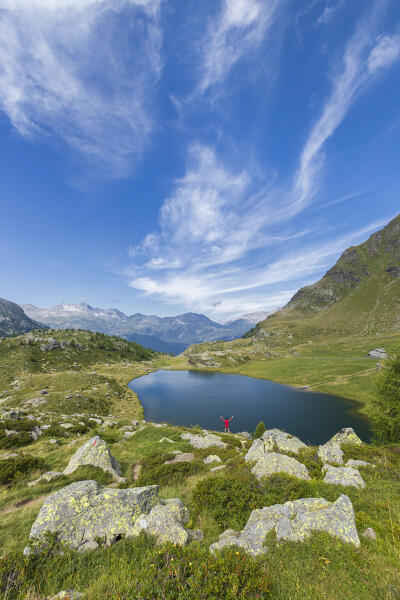 Hiker triumphing at lake Angeloga, Alpe Angeloga, Campodolcino, Sondrio province, Spluga valley Lombardy, Italy, Europe (MR)
