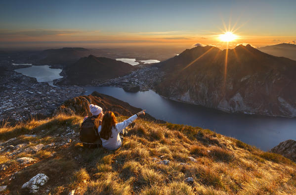 Lake Como, Lombardy, Italy. Two friends watching a scenic sunset from above Lecco city.