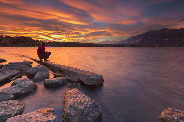 Man admire an incredible sunset of lenticular clouds on lake Annone, Annone di brianza, Lecco province, Brianza, Lombardy, Italy, Europe (MR)