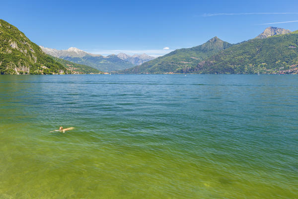 Girl takes a refreshing swim in the lake Como in summer time, Menaggio, Como province, Lombardy, Italy, Europe