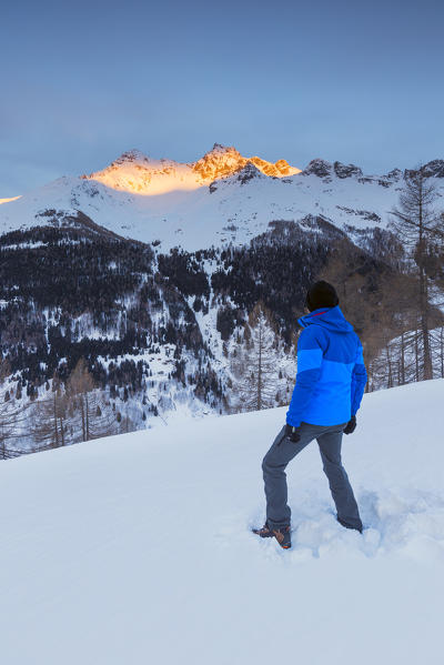 Hiker admire Pizzo Ferré and Pizzo dei Piani burning up at the first rays of sunrise, Spluga valley, Sondrio province, Lombardy, Italy, Europe (MR)