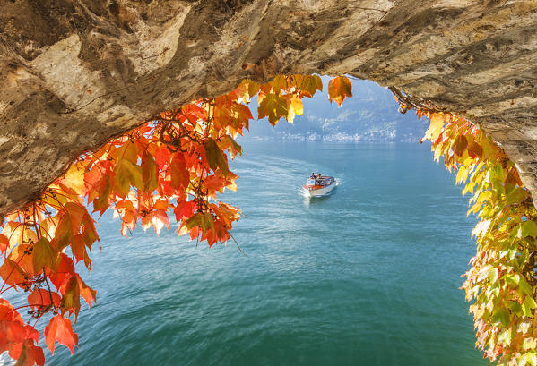 Autumn foliage frame the people that boat on lake Como to visit Nesso village, Como province, Lombardy, Italy, Europe