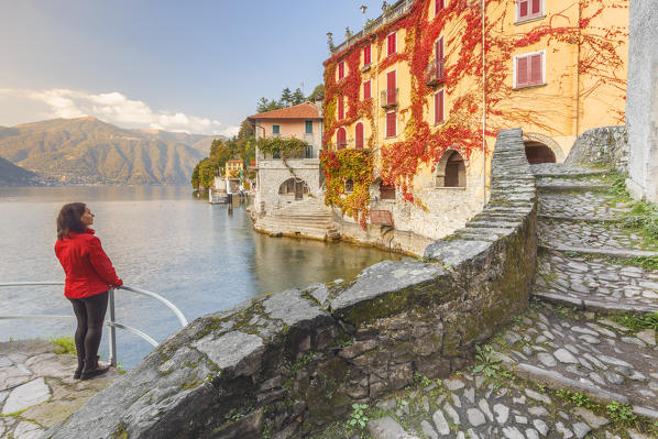 A tourist admire red ivy of Nesso village, Como lake, Como province, Lombardy, Italy, Europe (MR)