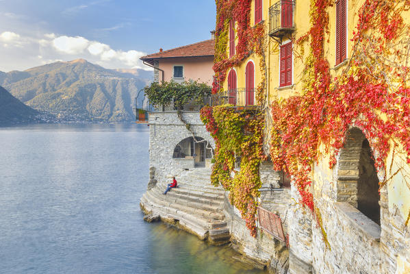 A man sitting on the steps of Nesso village admire the lake of Como, Como province, Lombardy, Italy, Europe (MR)