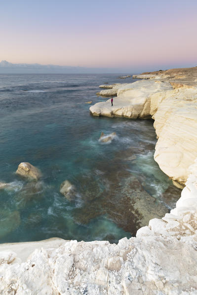 Cyprus, Limassol, woman standing at dawn on the cliff near the sea at Governor's beach