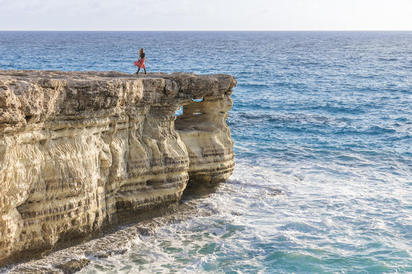 Cyprus, Ayia Napa, woman walking alone on cliff at the sea caves of Cape Greco