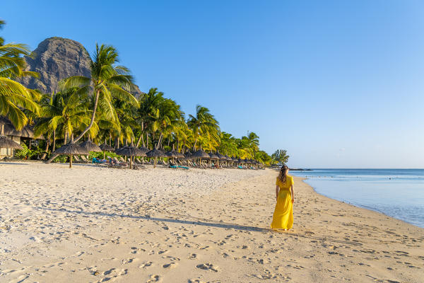 A young woman is walking on the the beach of the Beachcomber Paradis Hotel, Le Morne Brabant Peninsula, Black River (Riviere Noire), Mauritius (MR) (PR)
