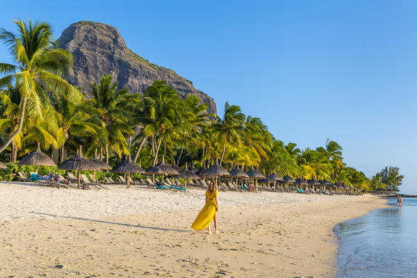 A young woman is walking on the the beach of the Beachcomber Paradis Hotel, Le Morne Brabant Peninsula, Black River (Riviere Noire), Mauritius