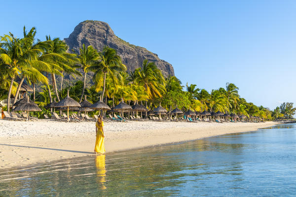 A young woman is walking on the the beach of the Beachcomber Paradis Hotel, Le Morne Brabant Peninsula, Black River (Riviere Noire), Mauritius (MR) (PR)