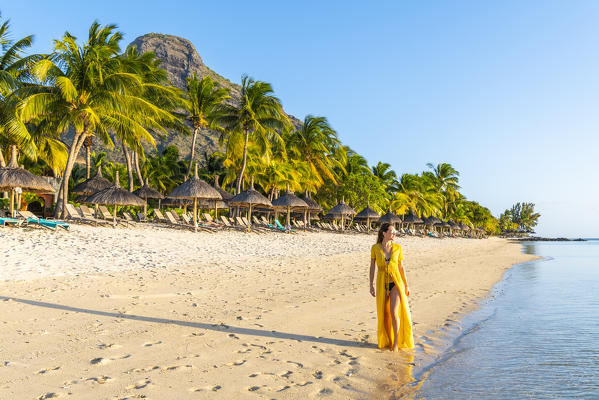 A young woman is walking on the the beach of the Beachcomber Paradis Hotel, Le Morne Brabant Peninsula, Black River (Riviere Noire), Mauritius (MR) (PR)