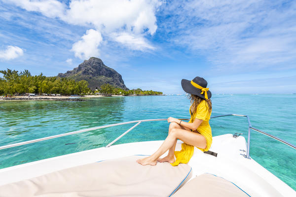 A young woman is relaxing on a boat in Le Morne bay. Le Morne Brabant Peninsula, Black River (Riviere Noire), Mauritius, Africa