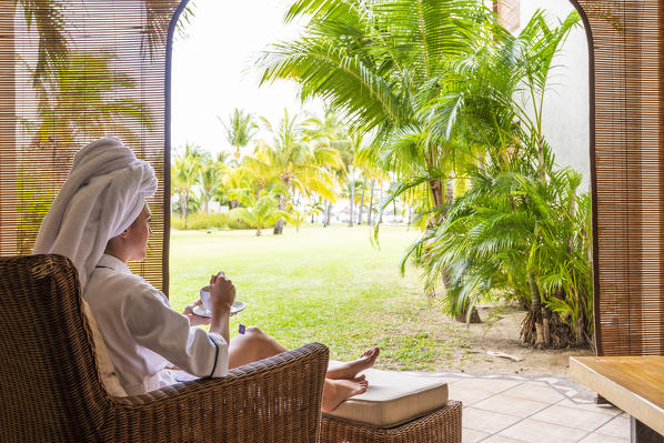 A young woman in bathrobe is relaxing in the Beachcomber Paradis Hotel, Le Morne Brabant Peninsula, Black River (Riviere Noire), Mauritius (MR) (PR)