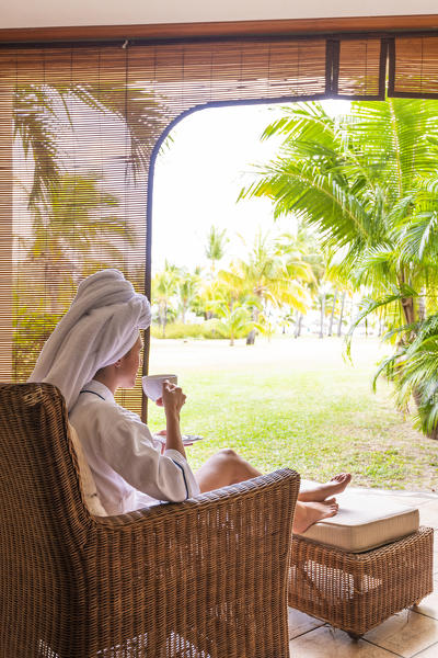 A young woman in bathrobe is relaxing in the Beachcomber Paradis Hotel, Le Morne Brabant Peninsula, Black River (Riviere Noire), Mauritius
