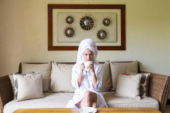 A young woman in bathrobe is relaxing in the Beachcomber Paradis Hotel, Le Morne Brabant Peninsula, Black River (Riviere Noire), Mauritius