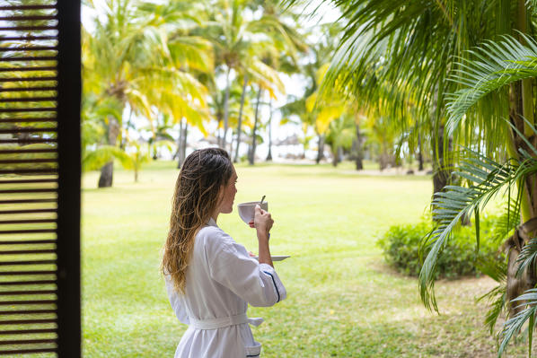A young woman in bathrobe is relaxing in the Beachcomber Paradis Hotel, Le Morne Brabant Peninsula, Black River (Riviere Noire), Mauritius