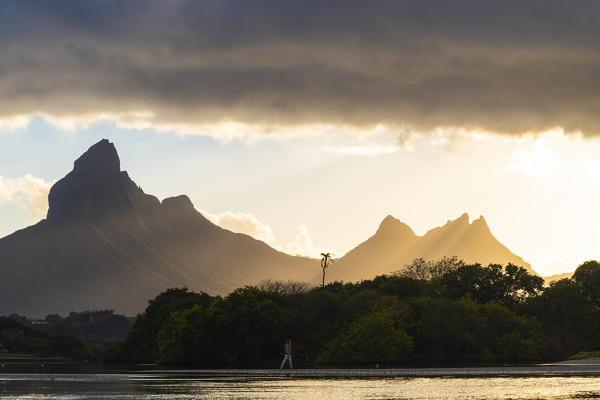 A woman is walking in Tamarin bay during the sunrise. Tamarin, Black River (Riviere Noire), Mauritius, Africa