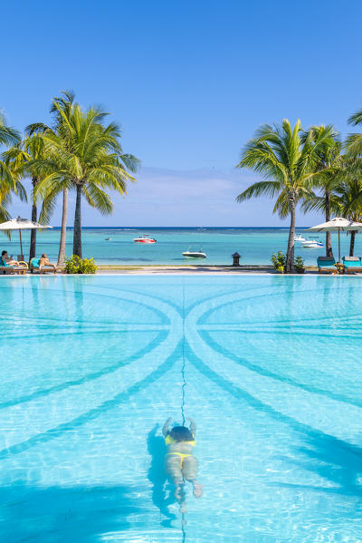 A young woman relaxing at the swimming pool of the Beachcomber Paradis Hotel, Le Morne Brabant Peninsula, Black River (Riviere Noire), Mauritius