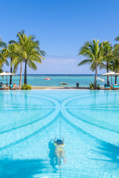 A young woman relaxing at the swimming pool of the Beachcomber Paradis Hotel, Le Morne Brabant Peninsula, Black River (Riviere Noire), Mauritius