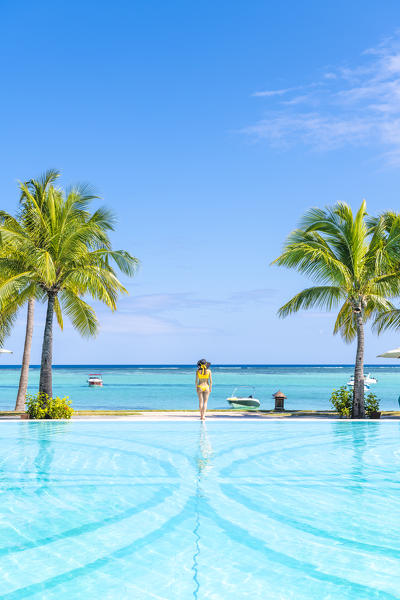 A young woman relaxing at the swimming pool of the Beachcomber Paradis Hotel, Le Morne Brabant Peninsula, Black River (Riviere Noire), Mauritius