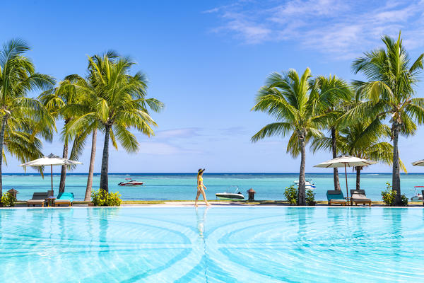 A young woman relaxing at the swimming pool of the Beachcomber Paradis Hotel, Le Morne Brabant Peninsula, Black River (Riviere Noire), Mauritius