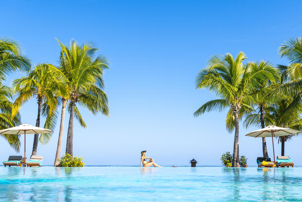 A young woman relaxing at the swimming pool of the Beachcomber Paradis Hotel, Le Morne Brabant Peninsula, Black River (Riviere Noire), Mauritius (MR) (PR)