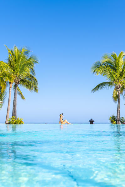 A young woman relaxing at the swimming pool of the Beachcomber Paradis Hotel, Le Morne Brabant Peninsula, Black River (Riviere Noire), Mauritius (MR) (PR)