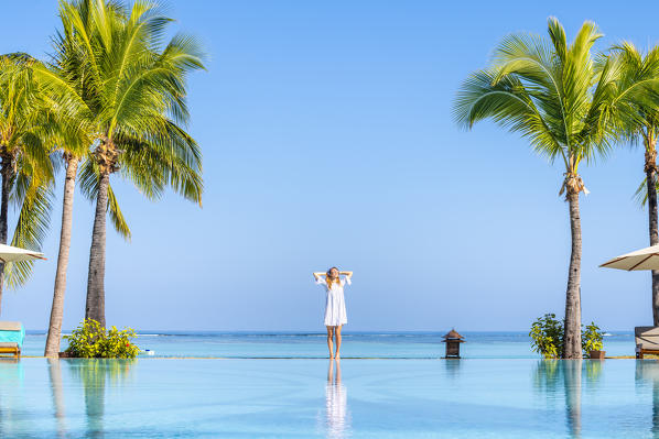 A young woman relaxing at the swimming pool of the Beachcomber Paradis Hotel, Le Morne Brabant Peninsula, Black River (Riviere Noire), Mauritius (MR) (PR)