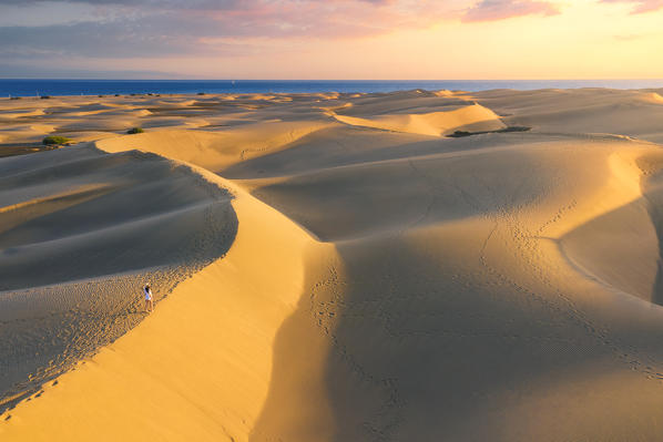 Tourist walking on sand dunes at sunset. Maspalomas, Las Palmas, Gran Canaria, Canary Islands, Spain, Europe