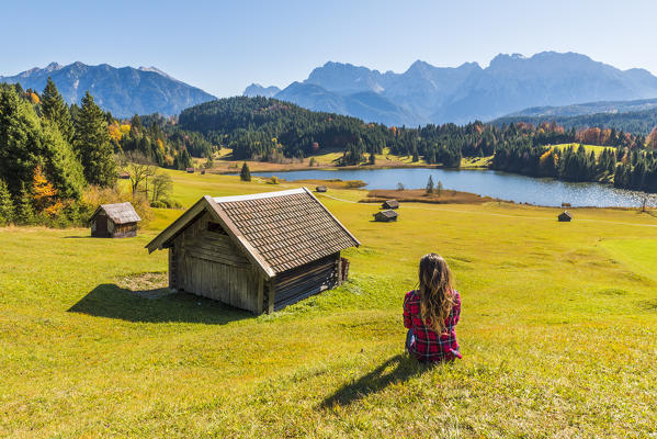 Gerold, Garmisch Partenkirchen, Bavaria, Germany, Europe. Young woman relaxing on a meadow near lake Geroldsee, Karwendel range in the background