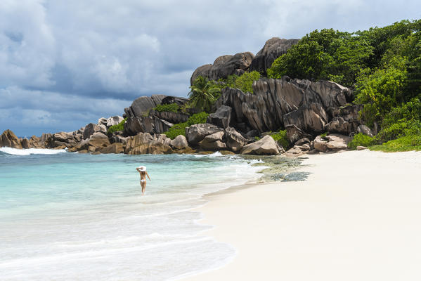A young lady strolling along Grand Anse. La Digue island, Seychelles, Africa  