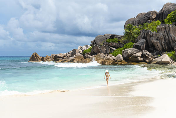 A young lady strolling along Grand Anse. La Digue island, Seychelles, Africa  
