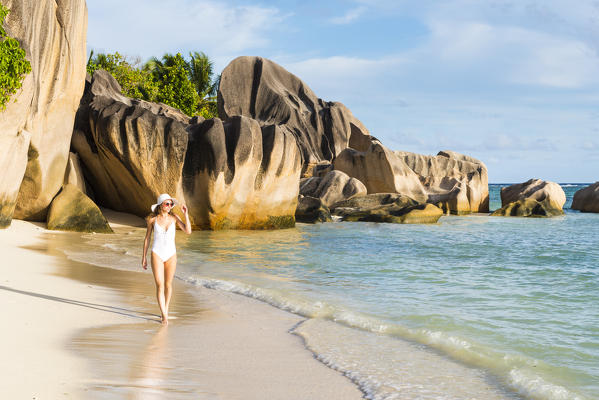 Beautiful young woman strolling along Anse Source d'Argent beach. La Digue island, Seychelles, Africa (MR)
