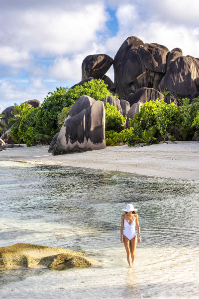 Beautiful young woman strolling along Anse Source d'Argent beach. La Digue island, Seychelles, Africa (MR)
