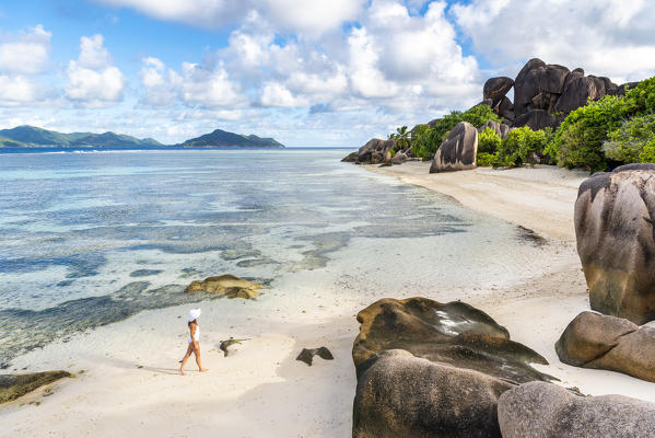 Beautiful young woman strolling along Anse Source d'Argent beach. La Digue island, Seychelles, Africa  