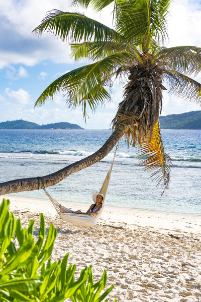 A woman relaxing on a hammock. La Digue, Seychelles, Africa (MR)