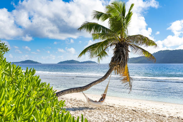 A woman relaxing on a hammock. La Digue, Seychelles, Africa (MR)