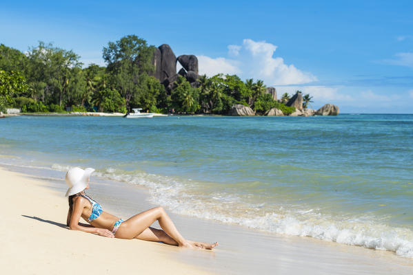 A beautiful woman enjoys the sun near Anse Source d'Argent beach. La Digue, Seychelles, Africa (MR)