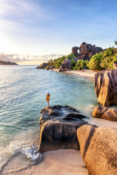 A young woman admires the sunset at Anse Source d'Argent, La Digue, Seychelles, Africa (MR)